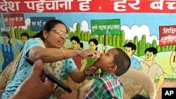 A health worker gives polio vaccine to a child at a school in New Delhi, India, April 7, 2013. 
