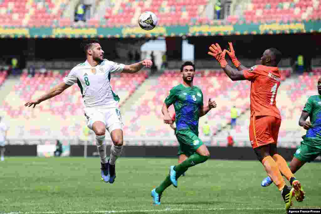 Algeria&#39;s forward Youcef Belaili (L) fights for the ball with Sierra Leone&#39;s goalkeeper Mohamed Nbalie Kamara (R).