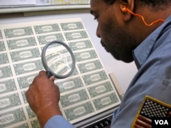 A worker at the Bureau of Engraving and Printing examines sheets of US currency before they are made into wallet-ready bills. (J. Taboh/VOA)