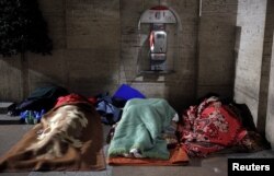 FILE - Homeless people sleep in passageway near St. Peter's square in Rome, Italy, Jan. 11, 2017.