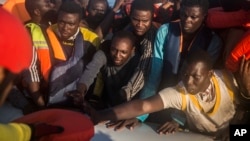 In this Thursday, July 28, 2016 photo, about 150 sub-Saharan refugees and migrants receive life jackets as they aboard an overcrowded rubber boat and wait to be assisted by an NGO during a rescue operation on the Mediterranean Sea, about 23 kilometers (14 miles) north of Sabratha, Lybia. 