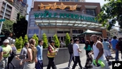 FILE - Pedestrians walk past a Whole Foods Market, down the street from the headquarters of Amazon, in Seattle, Washington, July 11, 2017.