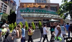 FILE - Pedestrians walk past a Whole Foods Market, just down the street from the headquarters of Amazon, in Seattle, Washington, July 11, 2017.