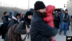 Refugees and migrants wait for police and military vans on a highway near the Greek village of Thourio, at the Greek-Turkish border, Jan. 24, 2016. The migrants told police they were part of a group of 130 who crossed the Evros River between Greece and Tu
