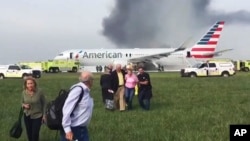 In this photo provided by passenger Jose Castillo, fellow passengers walk away from a burning American Airlines jet that aborted its takeoff and caught fire on the runway at Chicago's O'Hare International Airport, Oct. 28, 2016. 