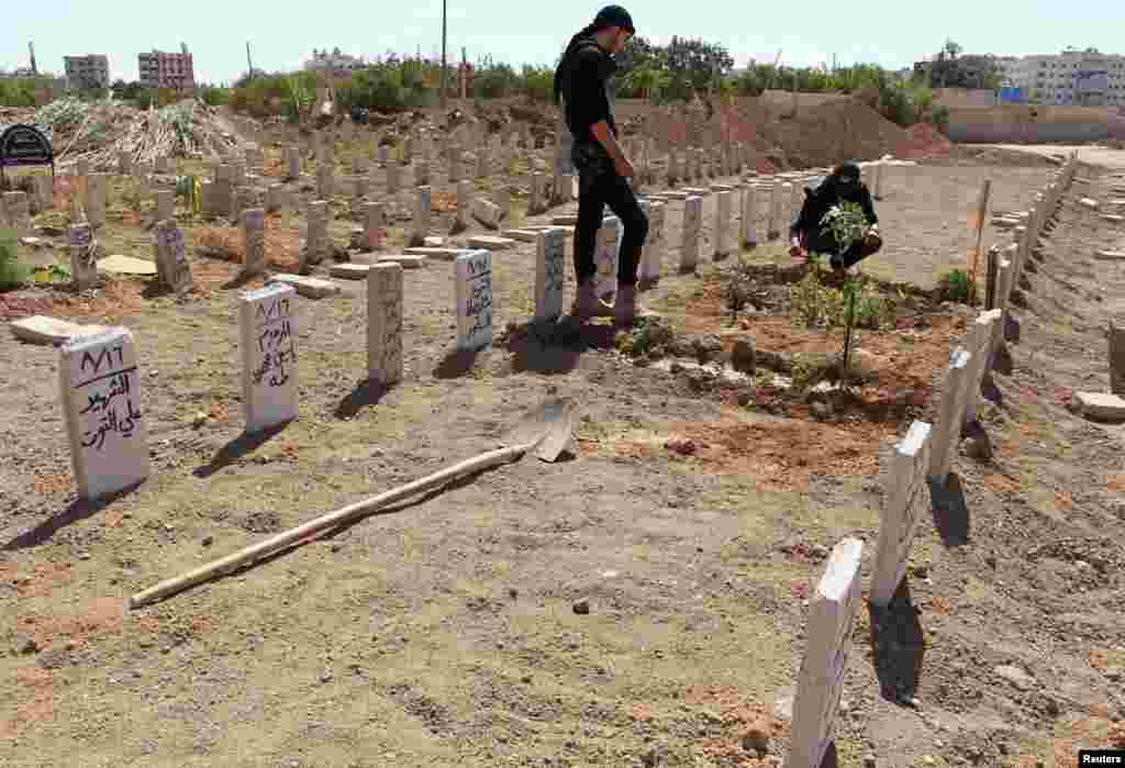 Free Syrian Army fighters visit the grave of their comrade who was killed in a recent attack, in a cemetery in Duma neighborhood in Damascus, Sept. 25, 2013. 