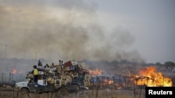 A truck piled with furniture and other items drives past burning businesses and homesteads, locally known as "tukuls", in the center of Abyei, central Sudan in this handout photograph released on May 28, 2011.