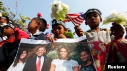 A girl holds a portrait of U.S. President Barack Obama and his family during a rally in front of the U.S Embassy in Phnom Penh, March 17, 2015.