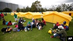 Venezuelan migrants sit upon arrival to a new, refugee-style camp set up by the government in Bogota, Colombia, Nov. 13, 2018. 