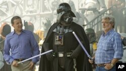 El presidente y CEO de Disney, Bob Iger, izquierda, y el creador de Star Wars, George Lucas, juegan con el personaje de Darth Vader. Disney compró los estudios LucasFilm. 