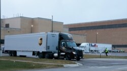 Truk-truk keluar dari fasilitas pabrik Pfizer di Portage, Michigan, Minggu (13/12).