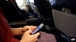 Una pasajera revisa su teléfono móvil dentro de un avión. La TSA ha ordenado nuevas medidas de seguridad respecto de los aparatos electrónicos.