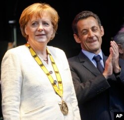 On May 1, 2008, German Chancellor Angela Merkel and then-French President Nicolas Sarkozy stand on a stage after the Charlemagne Prize was awarded to Merkel in Aachen, Germany.