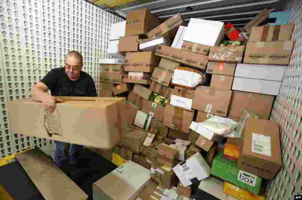 An employee of DHL, a division of German postal service Deutsche Post, unloads parcels from a transport vehicle at the company&#39;s logistics center in Gross Schwass near Rostock. During the pre-Christmas period, around 12,000 parcels per day are handled at the center, which is the double amount of pieces than usual, Dec. 18, 2013.