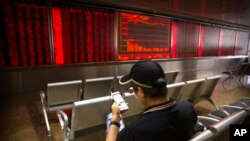 2019年9月5日亞洲股市大多上揚。一名男子坐在北京一家股票交易所的電子屏幕前看手機。