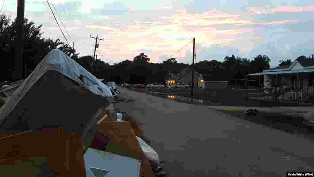 Residents of St. Amant, La., clear flood-damaged household goods out of their homes, Aug. 22, 2016.