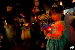 FILE - a girl plays with an electronic toy while standing with her family at a Mother's Day-themed disco dance party for children in Beijing.