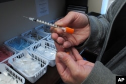 FILE - Paula Maupin, the public health nurse for eastern Indiana's Fayette County, holds one of the syringes provided to intravenous drug users taking part in the county's state-approved needle exchange program, which is housed in the county courthouse.
