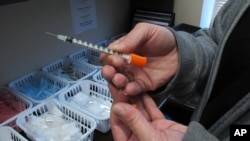 FILE - A nurse for eastern Indiana's Fayette County holds one of the syringes provided to intravenous drug users taking part in the county's state-approved needle exchange program in Connersville. The effort is in response to a hepatitis C outbreak among IV drug users.