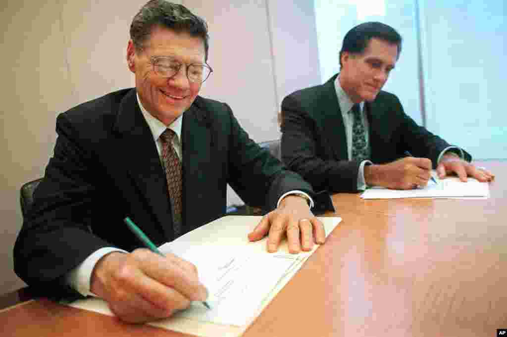 Thomas S. Monaghan, founder and chairman of Domino&#39;s Pizza, Inc., left, and Mitt Romney, managing director of Bain Capital, Inc., sign an agreement for Monaghan to sell a &quot;significant portion&quot; of his stake in the company to Bain Capital in New York, September 25, 1996.
