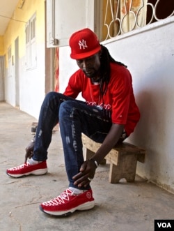 Babacar Cissokho shows the shoes he makes and sells to make a living after 5½ years in prison. (A. Grovestins/VOA)