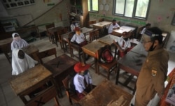 Siswa dan guru memakai masker pelindung setelah pemerintah membuka kembali sekolah dengan menerapkan proses pembelajaran tatap muka di tengah wabah Covid-19 di Pariaman, Sumatera Barat, 13 Juli 2020. (Foto: Antar /Iggoy el Fitra via Reuters)