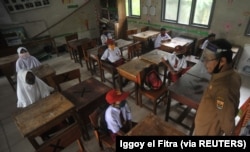Siswa dan guru memakai masker pelindung setelah pemerintah Indonesia membuka kembali sekolah dengan menerapkan proses pembelajaran tatap muka di tengah wabah Covid-19 di Pariaman, Provinsi Sumatera Barat, 13 Juli 2020. (Foto: Antar /Iggoy el Fitra/via Reu