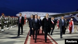 Tunisia's Prime Minister Youssef Chahed, front right, walks with his French counterpart Manuel Valls, left, upon his arrival at Tunis airport in Tunis, Tunisia, Nov. 28, 2016. 
