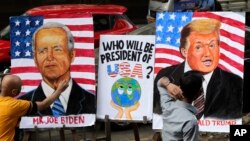 Guru seni India, Sagar Kambli, melukis Presiden Donald Trump dan pesaingnya Joe Biden di trotoar di luar sekolah seninya yang masih ditutup karena pandemi COVID-19 di Mumbai, India, Kamis, 29 Oktober 2020. (AP Photo / Rajanish Kakade)