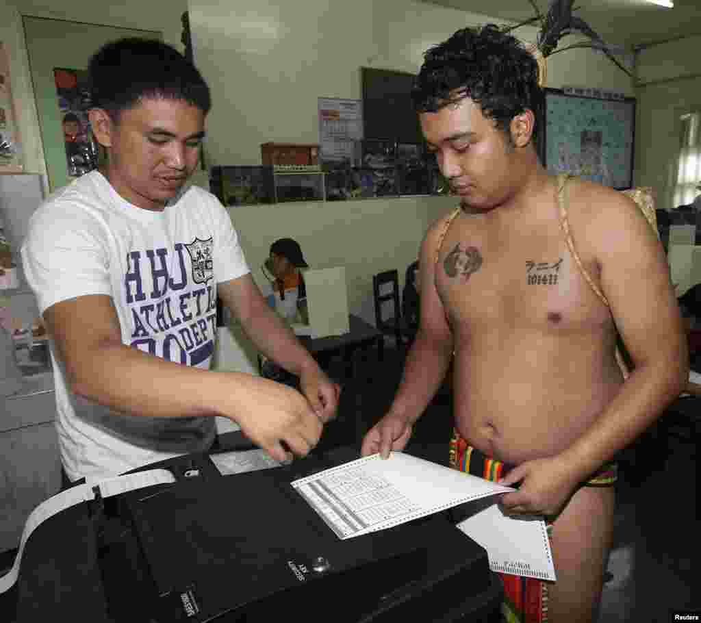 A member of a tribal &quot;Igorot&quot; family casts his vote through a voting machine during midterm elections in Baguio city, northern Philippines, May 13, 2013. 