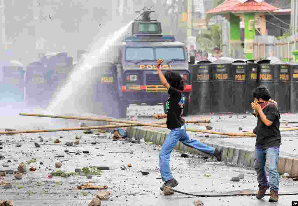 Indonesian students react as a police water cannon truck sprays water to disperse a rally commemorating the International Anti-Corruption Day that turned violent in Makassar, South Sulawesi.