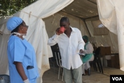 A medical staff member (left) administers oral rehydrating solution to a cholera patient to replace fluids he lost through diarrhea, in Harare, Zimbabwe, Sept. 12, 2018, (C. Mavhunga/VOA)