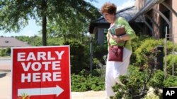 A library patron passes by a precinct sign outside the Roosevelt Thompson Library, May 7, 2018, as early voting opened in Little Rock, Arkansas. 