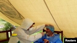 Petugas medis mengenakan APD, melakukan tes swab di Pusat Tanggap Darurat Layanan Kesehatan Aga Khan, Booni, Chitral, Pakistan. (Foto: Suhail Aziz/Handout via REUTERS)