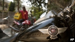 A delivery boy sits on his Indian motorcycle and looks at a Harley Davidson Fat Boy motorcycle parked in a residential area in New Delhi, India, March 1, 2017. 