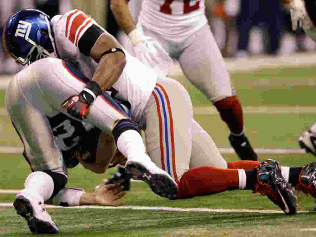 Pemain belakang New York Giants Justin Tuck (kanan) menjegal quarterback New England Patriots Tom Brady pada babak kedua Superbowl XLVI di Indianapolis, Indiana (AP).