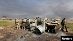 Iraqi security forces inspect a destroyed vehicle belonging to Islamic State militants on the outskirts of al-Alam, just north of Tikrit, March 9, 2015. 