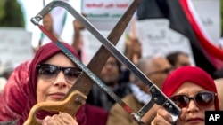 Des protestataires brandissant des scies lors d'une manifestation contre une visite du prince héritier saoudien MBS,Tunis, le 27 novembre 2018. 