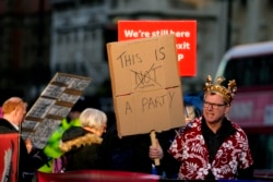 FILE - Protestors hold placards in Parliament Square as Britain's Prime Minister Boris Johnson attends the weekly Prime Ministers' Questions session in parliament in London, Jan. 12, 2022.
