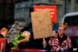 FILE - Protestors hold placards in Parliament Square as Britain's Prime Minister Boris Johnson attends the weekly Prime Ministers' Questions session in parliament in London, Jan. 12, 2022.