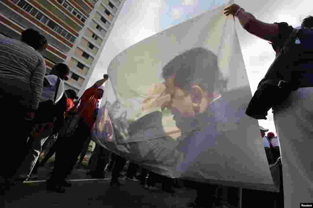 Venezuelan students carry a picture of President Hugo Chavez during a gathering in show of support in Havana, Cuba. The Venezuelan government is upbeat about the president&#39;s recovery from cancer surgery in Cuba, but the socialist maverick has not been seen in public or heard from in eight weeks.