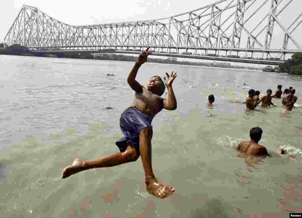 A boy jumps into the Ganges river to cool himself off on a hot summer day in Kolkata, India. Temperature in Kolkata is expected to reach 37 degrees Celsius (98.6 degrees Fahrenheit).