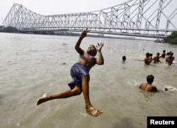 A boy jumps into the Ganges river to cool off himself on a hot summer day in Kolkata, India, May 6, 2015. Temperature in Kolkata on Wednesday is expected to reach 37 degree Celsius (98.6 degree Fahrenheit).