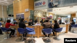FILE - Clients sit in a branch of the Bank for Investment and Development of Vietnam (BIDV), Hanoi.