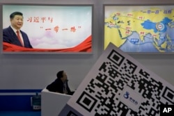 An attendee at a conference looks up near a portrait of Chinese President Xi Jinping with the words "Xi Jinping and One Belt One Road" and "One Belt One Road strategy," in Beijing, April 28, 2017. The “Belt and Road Forum” opens Sunday.