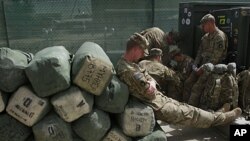 A U.S. soldier with Task Force Red Horse leans on baggage, as they wait out side of the customs office to leave Afghanistan at the U.S. base in Bagram, north of Kabul, Afghanistan, July 14, 2011