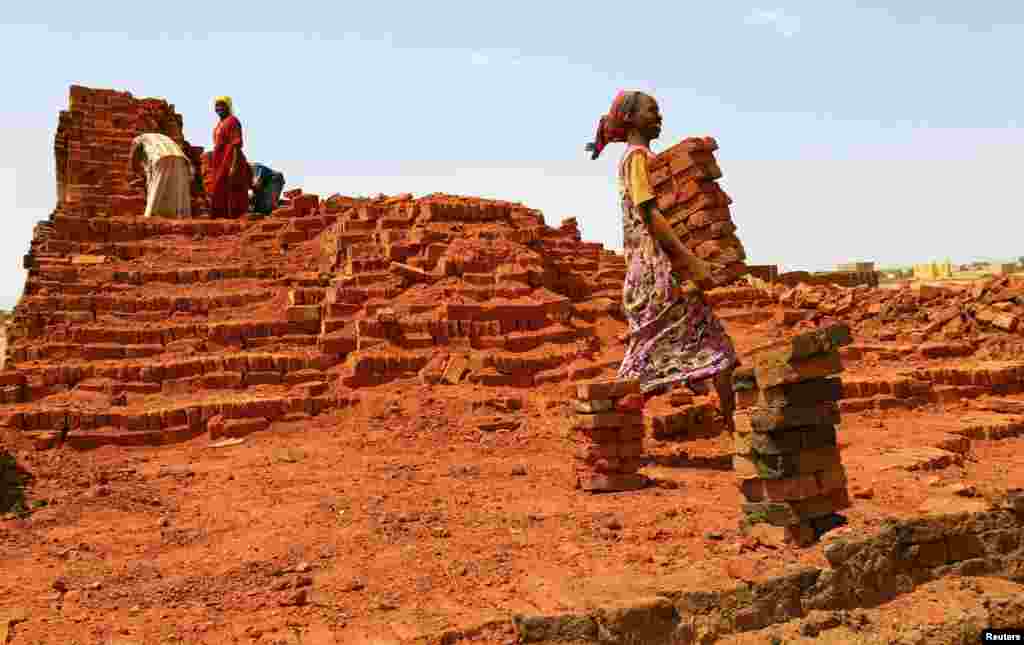 Seorang perempuan membawa batu-bata di kamp pengungsi Abu Shock di Al Fashir, Darfur utara, Sudan.