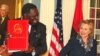 Razão para sorrir. Ministro dos Negócios Estrangeiros de Angola Assunção dos Anjos mostra o acordo assinado com Hillary Clinton