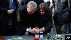 FILE - New York City Mayor Bill de Blasio and Paris Mayor Anne Hidalgo light candles in tribute to the victims of the terror attack against Charlie Hebdo at Place de la Republique in Paris, Jan. 20, 2015.