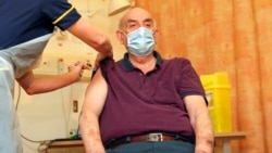 82-year-old Brian Pinker receives the Oxford University/AstraZeneca COVID-19 vaccine from nurse Sam Foster at the Churchill Hospital in Oxford, England, Monday, Jan. 4, 2021.